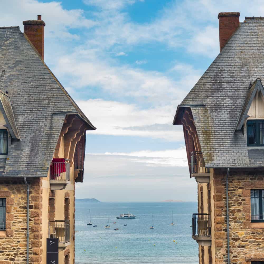 two traditional houses in the village of perros guirec, brittany, france, with the typical sloping roof made of slate. atlantic ocean with blue sky on the background.
